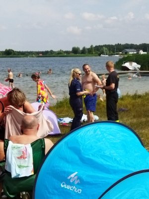 alt=&quot; Policjantka oraz strażak na plaży rozmawiają z mężczyzną. Na pierwszym planie niebieski namiot.&quot;