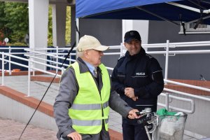 alt=&quot;Policjant oraz rowerzysta, który otrzymał kamizelkę odblaskową przed budynkiem KPP w Turku.&quot;