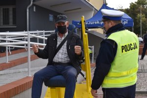 alt=&quot;Mężczyzna korzystający z symulatora zderzeń i policjant obsługujący symulator przed budynkiem KPP w Turku.&quot;