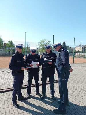 alt=&quot; Czterech policjantów omawiających wyniki turnieju.&quot;